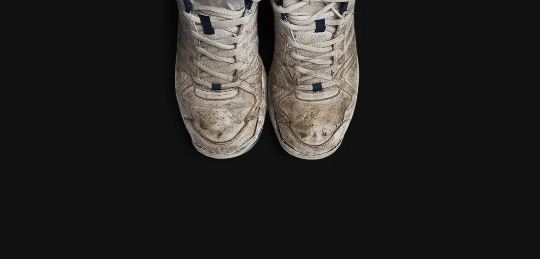 A pair of sneakers before cleaning, grey with ground-in dirt